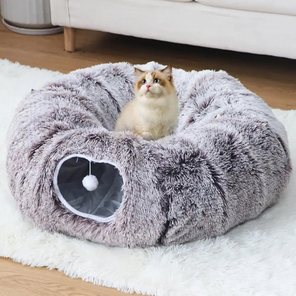 Cat sitting on a fluffy gray pet bed with a white ball inside, on a light-colored rug.