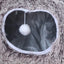 Close-up of a textured surface with a white pom-pom hanging inside a circular opening.